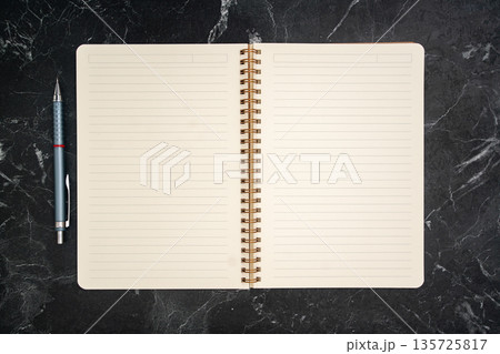 Open Spiral Notebook on Dark Marble Desk Background Open Spiral Notebook on Dark Marble Desk Background 135725817