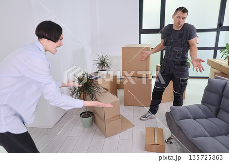 Frustration fills the room as a couple faces moving chaos and unorganized boxes while discussing their next steps Frustration fills the room as a couple faces moving chaos and unorganized boxes while discussing their next steps 135725863