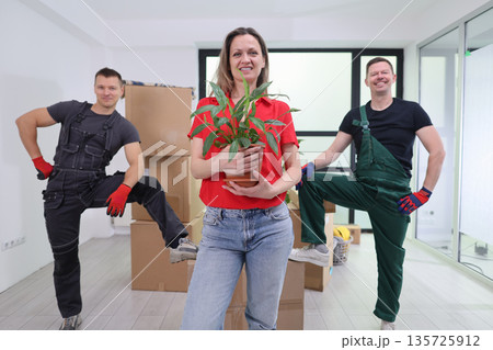 Cheerful team celebrating a successful move with a plant in a bright new space Cheerful team celebrating a successful move with a plant in a bright new space 135725912