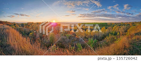 Stunning autumnal vista from a hilltop overlooking the multicolored forest canopy basking in the soft sunset light. Vibrant trees create a mosaic of fall colors, stretching toward the horizon Stunning autumnal vista from a hilltop overlooking the multicolored forest canopy basking in the soft sunset light. Vibrant trees create a mosaic of fall colors, stretching toward the horizon 135726042