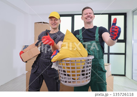 Cheerful movers organizing a new apartment surrounded by packed boxes and bright sunlight Cheerful movers organizing a new apartment surrounded by packed boxes and bright sunlight 135726118