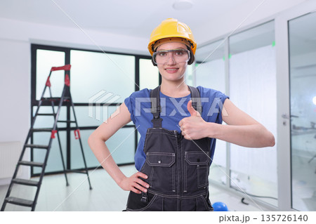 Busy construction site where a woman stands proudly in a hard hat and overalls, ready to tackle tasks with a smile and enthusiasm Busy construction site where a woman stands proudly in a hard hat and overalls, ready to tackle tasks with a smile and enthusiasm 135726140