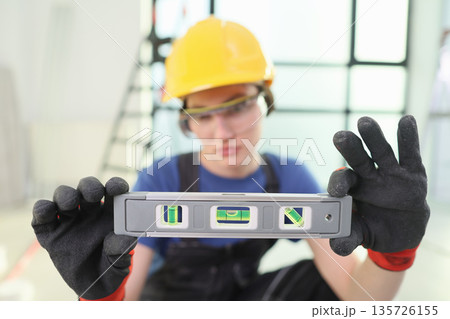 Skilled worker checks level with precision tool during renovation in modern building Skilled worker checks level with precision tool during renovation in modern building 135726155