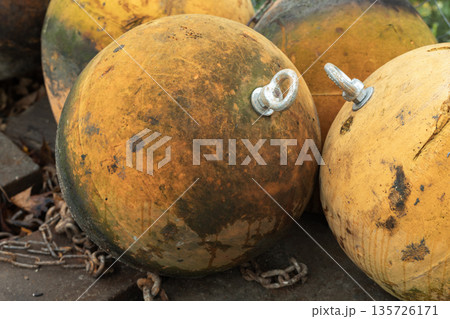 A cluster of worn nautical buoys in orange and yellow tones 135726171