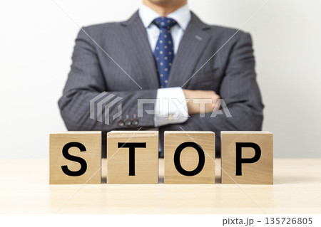 「STOP 」と書かれたブロックと腕組みをするビジネスマン 「STOP 」と書かれたブロックと腕組みをするビジネスマン 135726805