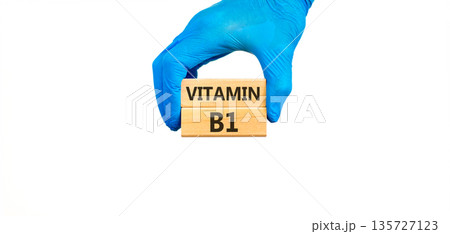 Vitamin B1 symbol. Concept words Vitamin B1 on beautiful wooden blocks. Doctor's hand in blue medical glove. Beautiful white background. Medical healthy lifestyle Vitamin B1 concept. Vitamin B1 symbol. Concept words Vitamin B1 on beautiful wooden blocks. Doctor's hand in blue medical glove. Beautiful white background. Medical healthy lifestyle Vitamin B1 concept. 135727123