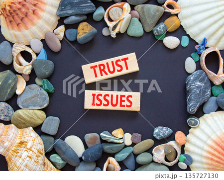 Trust issues symbol. Concept word Trust issues on beautiful wooden blocks. Beautiful black paper background. Beautiful sea stones and sea shells. Business trust issues concept. Copy space. Trust issues symbol. Concept word Trust issues on beautiful wooden blocks. Beautiful black paper background. Beautiful sea stones and sea shells. Business trust issues concept. Copy space. 135727130