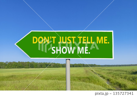 Tell or show symbol. Concept words Do not just tell me, show me beautiful green road sign. Beautiful blue sky green field background. Business tell or show concept. Copy space. 135727341