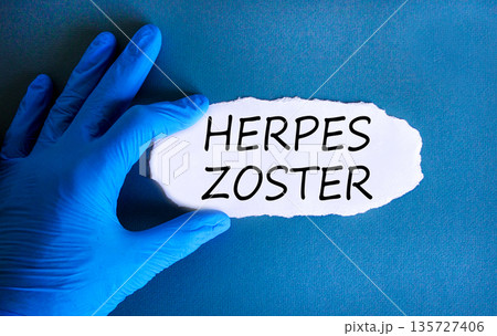 Herpes zoster symbol. Concept words Herpes zoster on beautiful white paper. Doctor's hand in blue medical glove. Beautiful blue background. Medical healthy lifestyle herpes zoster concept. 135727406