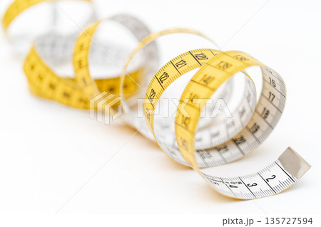 Yellow measuring tape on white background. Measurement of length and circumference. Lose weight and get fat. 135727594