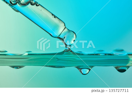 Pipette dripping blue liquid in science lab Pipette dripping blue liquid in science lab 135727711