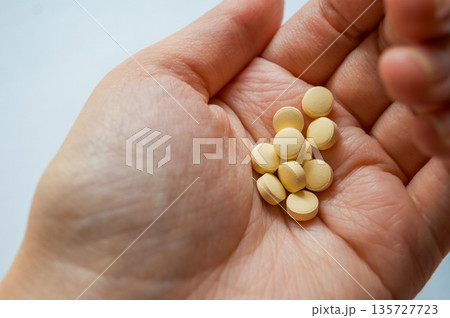 Human hand holding multiple yellow tablets 135727723