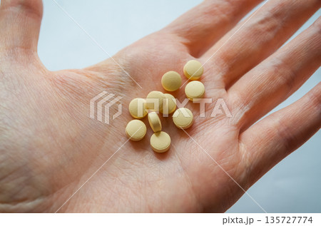Human hand holding multiple yellow tablets 135727774
