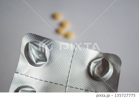 Used aluminum blister pack with yellow pills in the background 135727775