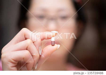 カプセル型の薬を持った女性 135728486