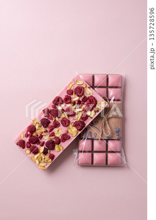 Chocolate bar with freeze-dried berries and nuts on pink background 135728596