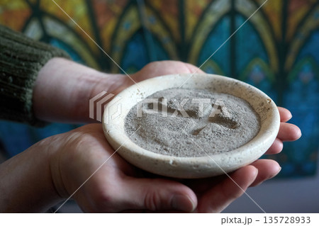 Hands holding ash wednesday ashes with cross symbol 135728933