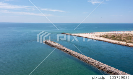 Serene coastal view featuring a stone jetty extending into calm turquoise waters, ideal for relaxation and beach activities. Tavira Portugal Algarve 135729085