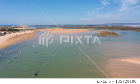 Drone captures Ria Formosa and Praia de Faro showing calm waters, sandy areas, and people engaging with nature in Faro, Portugal on a sunny day Drone captures Ria Formosa and Praia de Faro showing calm waters, sandy areas, and people engaging with nature in Faro, Portugal on a sunny day 135729100