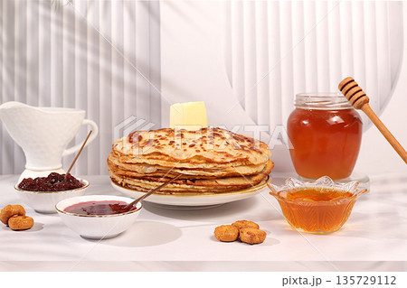 Delicious Russian pancakes with soft cheese, honey, jam, and sour cream on an elegant kitchen table. Maslenitsa concept and traditional Russian cuisine. Advertising banner for a cafe or restaurant. 135729112
