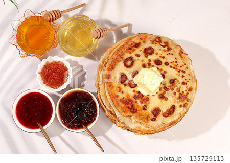 Delicious Russian pancakes with soft cheese, honey, jam, and sour cream on an elegant kitchen table. Advertising banner for a cafe or restaurant. Maslenitsa concept and traditional Russian cuisine. Delicious Russian pancakes with soft cheese, honey, jam, and sour cream on an elegant kitchen table. Advertising banner for a cafe or restaurant. Maslenitsa concept and traditional Russian cuisine. 135729113