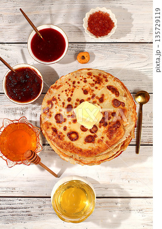 Delicious Russian pancakes with soft cheese, honey, jam, and sour cream on an elegant kitchen table. Maslenitsa concept and traditional Russian cuisine. Advertising banner for a cafe or restaurant 135729119