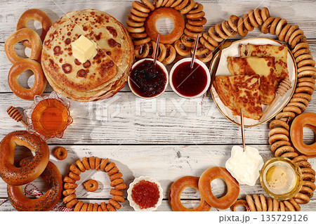 Maslenitsa concept and traditional Russian cuisine.Delicious Russian pancakes with soft cheese, honey, jam, sour cream, caviar and bagels, pretzels on the festive table.Advertising banner for a cafe 135729126