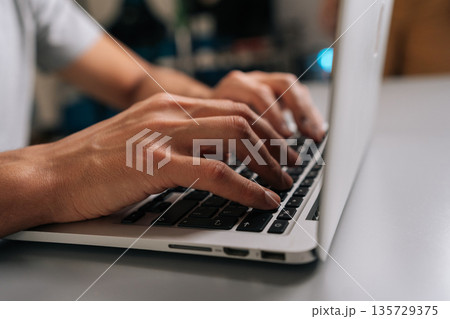 Close-up side view of unrecognizable freelancer male typing on laptop keyboard, professional home office scene showing remote work, coding, online learning, business tasks and digital communication. Close-up side view of unrecognizable freelancer male typing on laptop keyboard, professional home office scene showing remote work, coding, online learning, business tasks and digital communication. 135729375