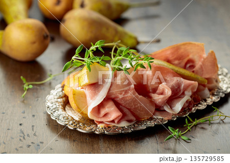 Prosciutto with pears and thyme on a silver tray. Prosciutto with pears and thyme on a silver tray. 135729585
