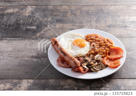 Full English breakfast with fried egg, bacon, sausages and beans Full English breakfast with fried egg, bacon, sausages and beans 135729823