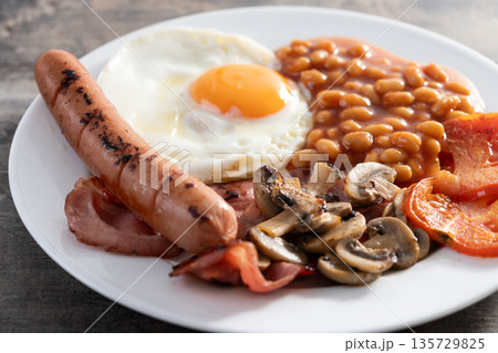 Full English breakfast with fried egg, bacon, sausages and beans Full English breakfast with fried egg, bacon, sausages and beans 135729825