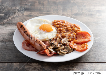 Full English breakfast with fried egg, bacon, sausages and beans Full English breakfast with fried egg, bacon, sausages and beans 135729826