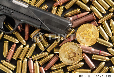 Bronze and brass gun bullets scattered on dark table, black pistol barrel, golden bitcoin coins near - illegal use of cryptocurrency to purchase weapon concept Bronze and brass gun bullets scattered on dark table, black pistol barrel, golden bitcoin coins near - illegal use of cryptocurrency to purchase weapon concept 135730346