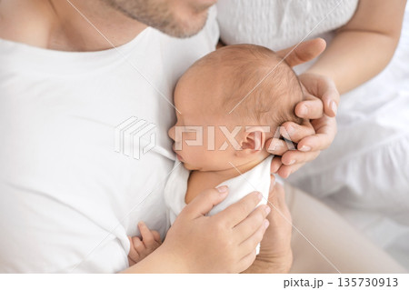 The father gently holds the newborn in his arms, hugging him tightly. Caring and love for children 135730913