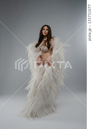 Studio portrait of a woman in a conceptual fantasy costume with white wings and a strappy harness. 135731077