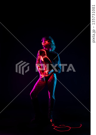 Cyberpunk woman in futuristic glowing glasses posing with neon light trails 135731081