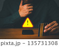 Person holding credit cards near smartphone with warning sign, symbolizing online payment fraud, credit card scam, and financial security risk. Concept of cybercrime prevention and digital safety. 135731308