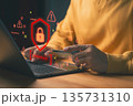 Person holding a credit card while using laptop, with red warning symbols and a digital padlock, representing online payment fraud, scam, cybersecurity threats, data breaches, and identity theft risk. 135731310