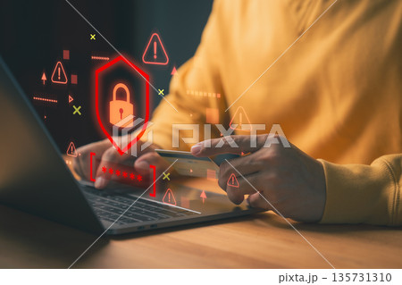 Person holding a credit card while using laptop, with red warning symbols and a digital padlock, representing online payment fraud, scam, cybersecurity threats, data breaches, and identity theft risk. 135731310