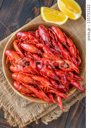 Wooden bowl of bright red boiled crawfish with lemon, rustic table Wooden bowl of bright red boiled crawfish with lemon, rustic table 135731322