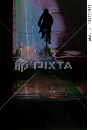 雨の日の光に照らされたアンダーパスのトンネルを自転車で駆け抜ける男性 雨の日の光に照らされたアンダーパスのトンネルを自転車で駆け抜ける男性 135731941
