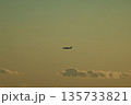 夕暮れの空を飛ぶ飛行機 135733821