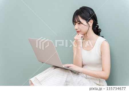 パソコンを見ながら真剣な表情で考える若いアジア人女性 パソコンを見ながら真剣な表情で考える若いアジア人女性 135734677