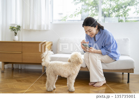 スマートフォンで愛犬の写真を撮るミドルの女性　犬との暮らし　イメージ 135735001