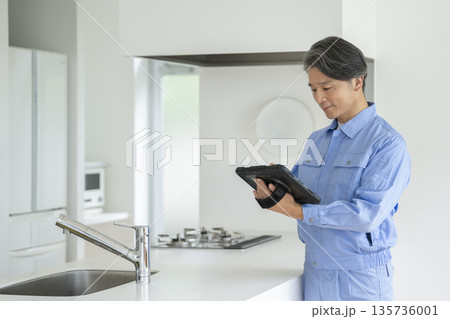 タブレットを持ってキッチンを点検する作業服を着たの男性 135736001