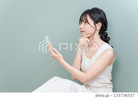 家でスマホを見ながら考える,検討する若いアジア人女性(悩む,真剣,検討,計画) 家でスマホを見ながら考える,検討する若いアジア人女性(悩む,真剣,検討,計画) 135736557
