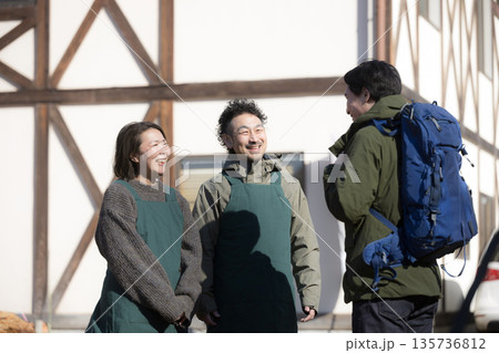 田舎で民宿やペンションを家族経営している接客や受付、チェックインの案内する夫婦と登山者 135736812