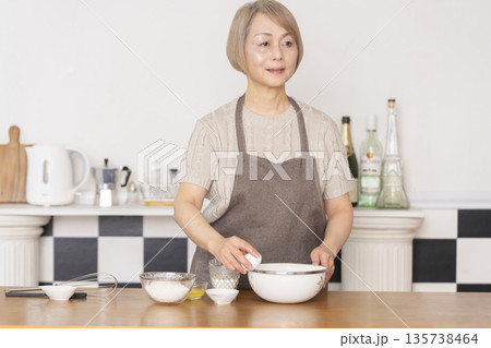 キッチンでアメリカンワッフルを焼くシニア女性 キッチンでアメリカンワッフルを焼くシニア女性 135738464