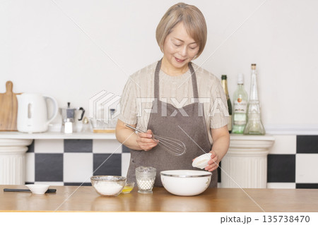 キッチンでアメリカンワッフルを焼くシニア女性 135738470