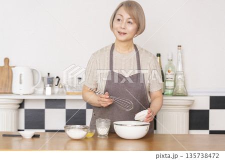 キッチンでアメリカンワッフルを焼くシニア女性 135738472